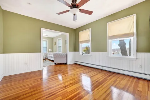 a view of an empty room with window and wooden floor