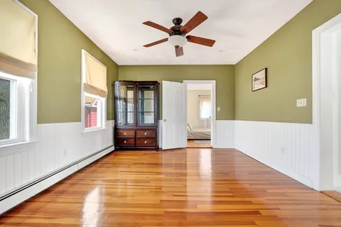 a view of an empty room with window and wooden floor