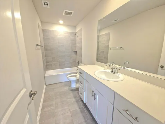 a spacious bathroom with a double vanity sink toilet mirror and shower