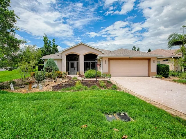 a view of a house with a big yard plants and large trees