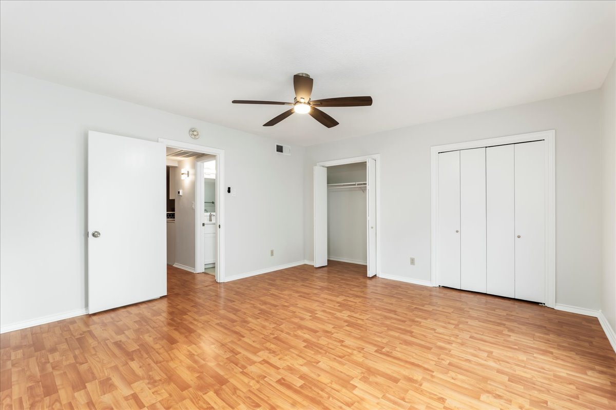 505 West 7th Street, Unit 313 Austin, TX 78701 - Photo 13 of 30 Unfurnished bedroom with multiple closets, visible vents, light wood-style floors, baseboards, and ceiling fan