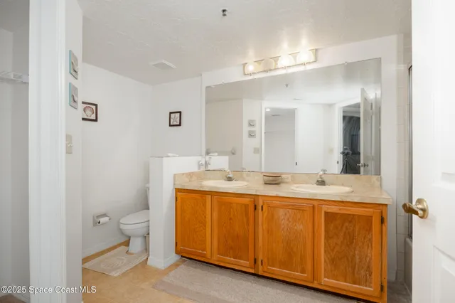 a bathroom with a granite countertop sink a toilet and a mirror