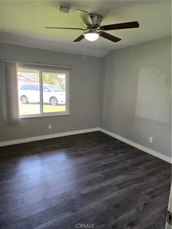 an empty room with wooden floor fan and windows