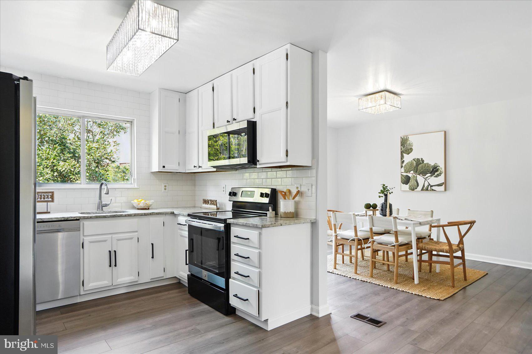 7020 Storch Lane Lanham, MD 20706 - Photo 11 of 44 a open kitchen with stainless steel appliances granite countertop a stove top oven a sink dishwasher and white cabinets with wooden floor