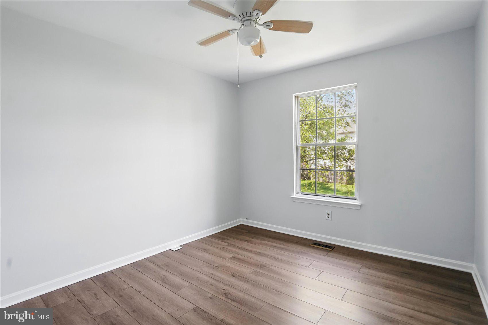 7020 Storch Lane Lanham, MD 20706 - Photo 30 of 44 an empty room with wooden floor chandelier fan and windows