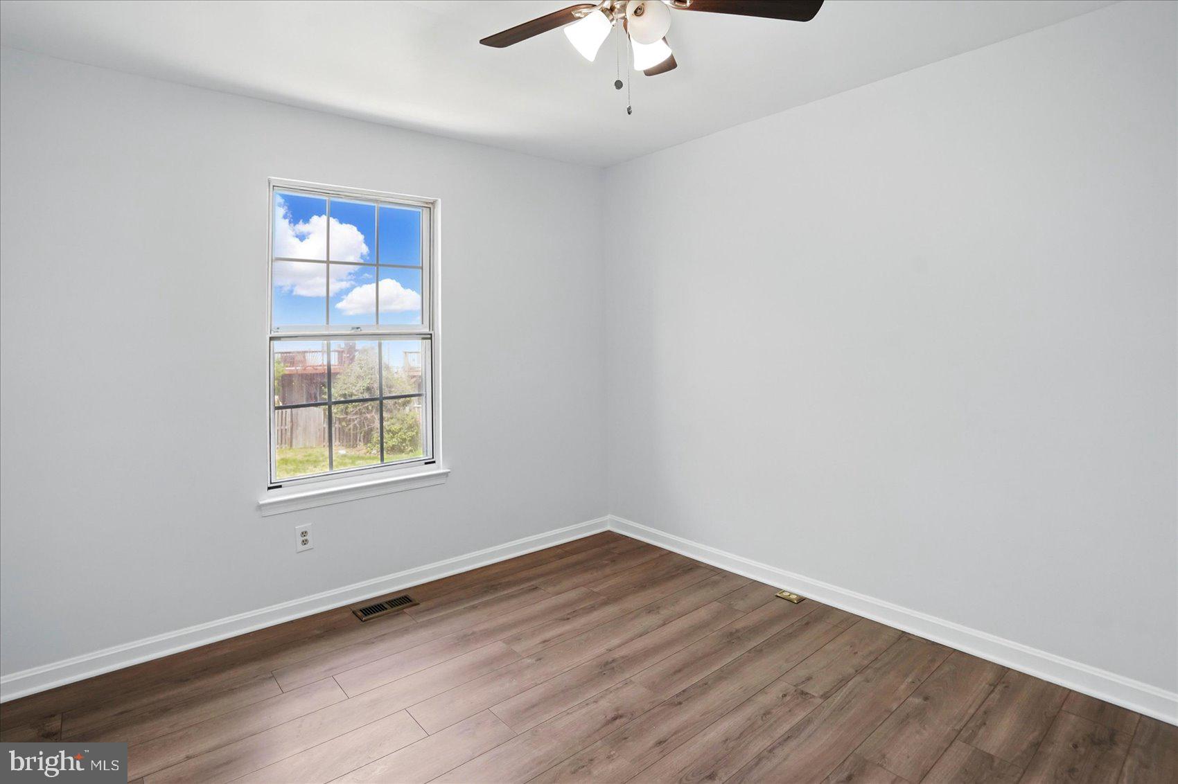 7020 Storch Lane Lanham, MD 20706 - Photo 32 of 44 an empty room with wooden floor chandelier fan and windows