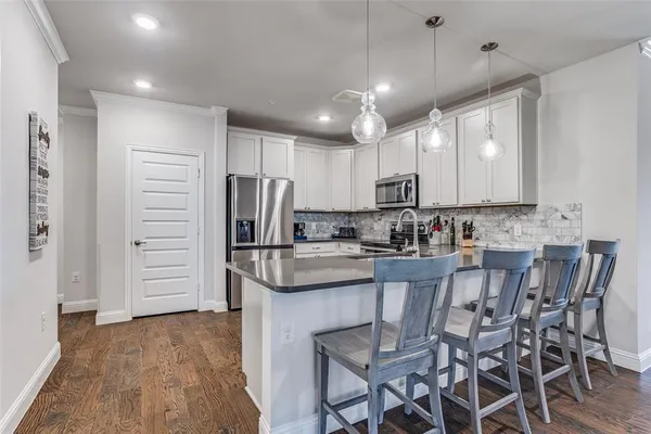 a kitchen with stainless steel appliances kitchen island granite countertop a table chairs refrigerator and cabinets