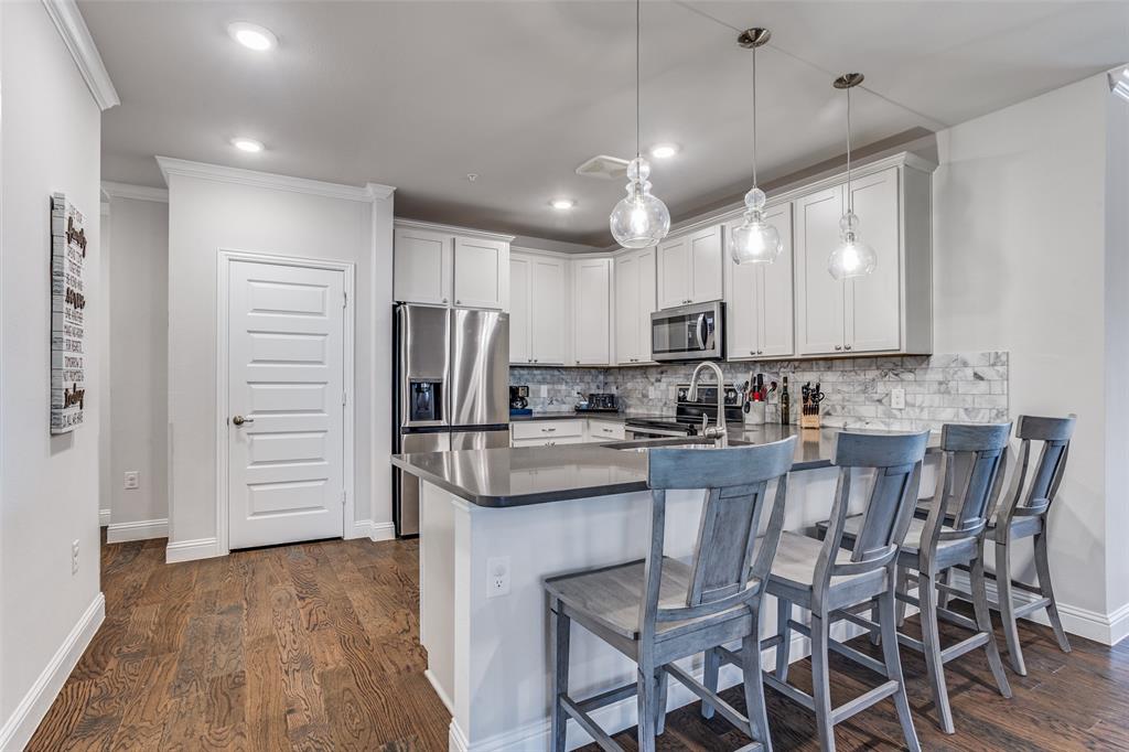 651 Watters Road, Unit 1206 Allen, TX 75013 - Photo 4 of 29 a kitchen with stainless steel appliances kitchen island granite countertop a table chairs refrigerator and cabinets