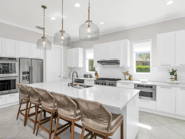 a kitchen with kitchen island granite countertop a sink a center island and appliances