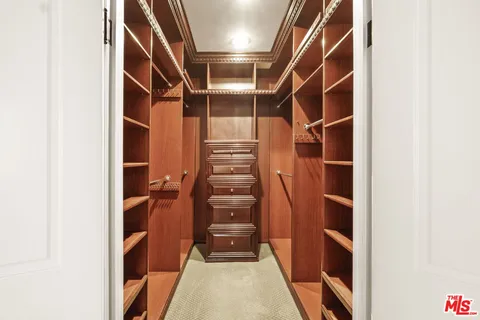 a view of walk in closet with clothes and shoes