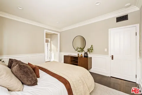 a bedroom with a large bed and wooden floor