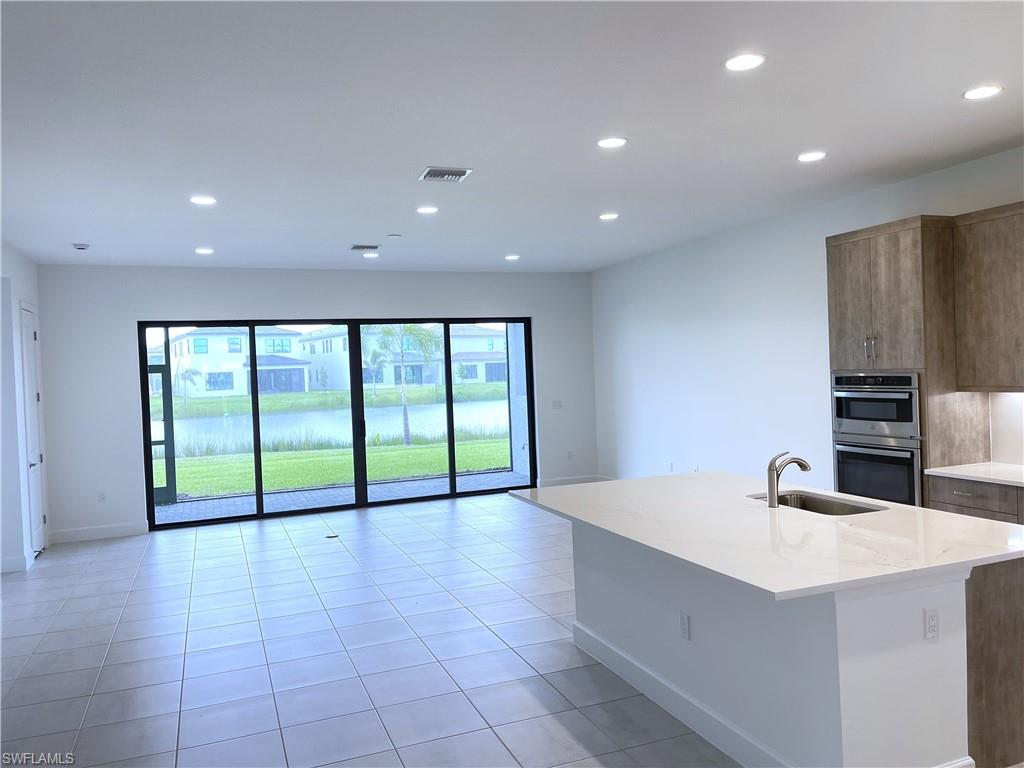 20909 Thistle Leaf Lane Estero, FL 33928 - Photo 3 of 18 a open kitchen with kitchen island a sink a stove and a view of living room