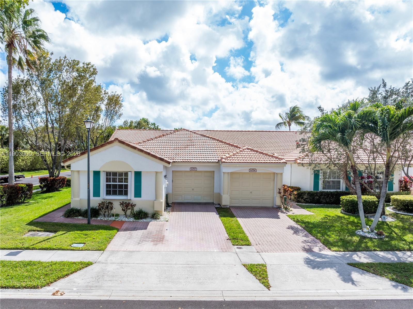 6050 Heliconia Road, Unit 6050 Delray Beach, FL 33484 - Photo 1 of 29 a front view of a house with a yard and potted plants