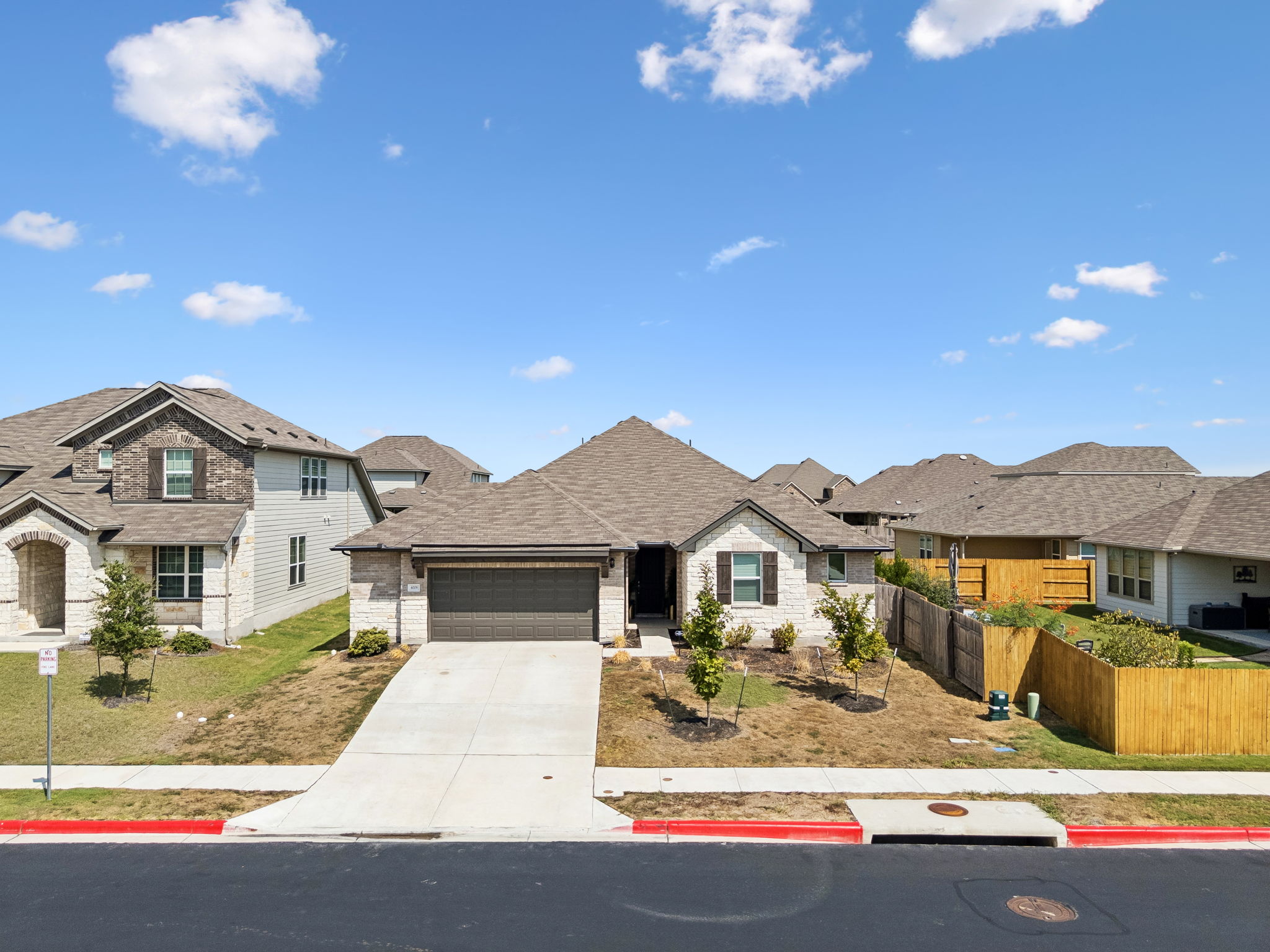 An inviting stone-accented facade showcases a clean concrete driveway and structured architectural lines.