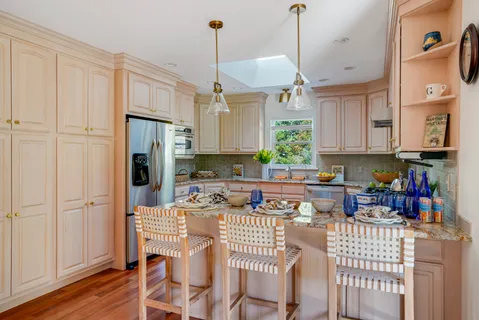 a kitchen with stainless steel appliances granite countertop a refrigerator a sink dishwasher a dining table and chairs with wooden floor