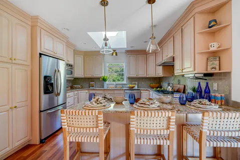 a kitchen with stainless steel appliances granite countertop a refrigerator a stove a sink dishwasher a dining table and chairs with wooden floor