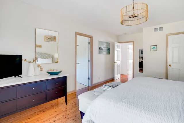 a bedroom with a large bed and a flat tv screen on dresser