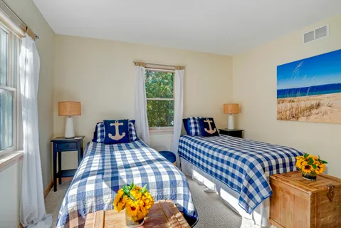 a bedroom with two beds and a lamp on dresser