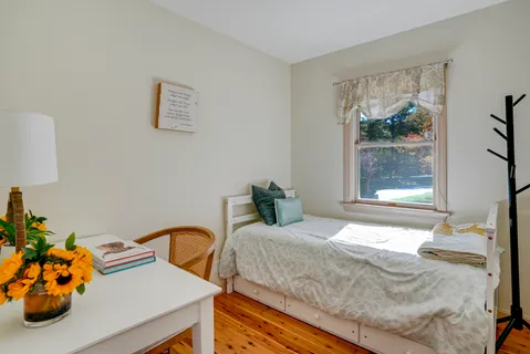 a bedroom with a bed and a dresser next to a window