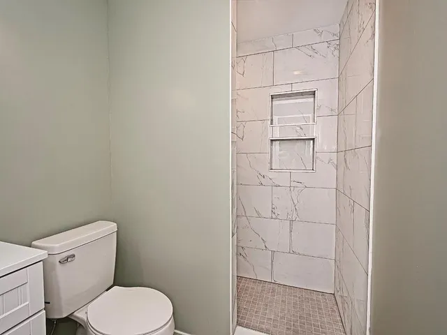 a white toilet sitting next to a shower