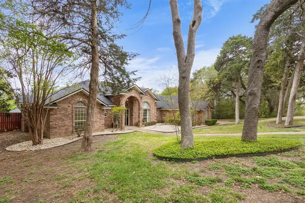 a front view of a house with a yard and large tree