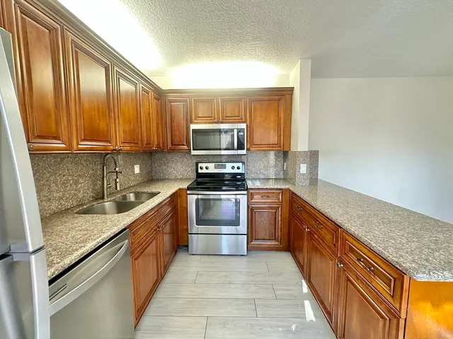 a kitchen with stainless steel appliances granite countertop a stove a sink and a microwave