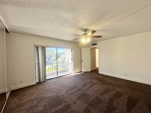 an empty room with chandelier fan and windows