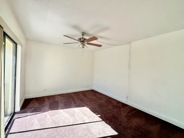 an empty room with a ceiling fan and a window