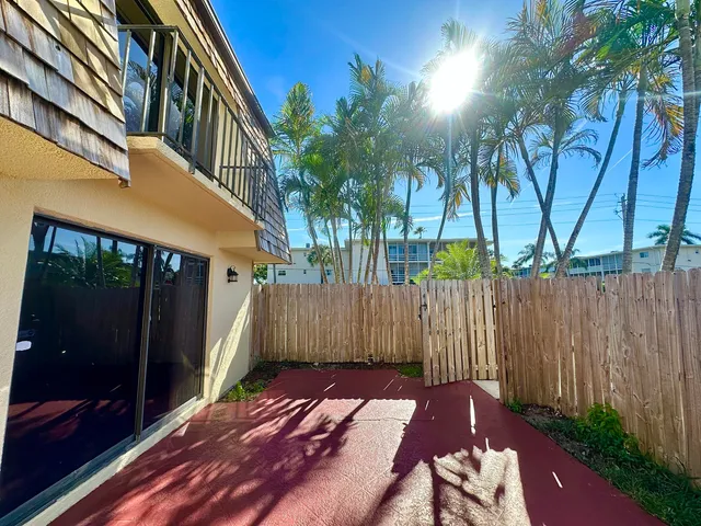 a view of a patio with table and chairs and couches with wooden floor and fence and a yard