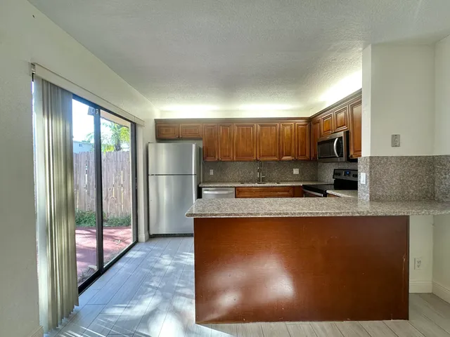 a kitchen with stainless steel appliances granite countertop a refrigerator a sink dishwasher a stove and a sink with granite countertops