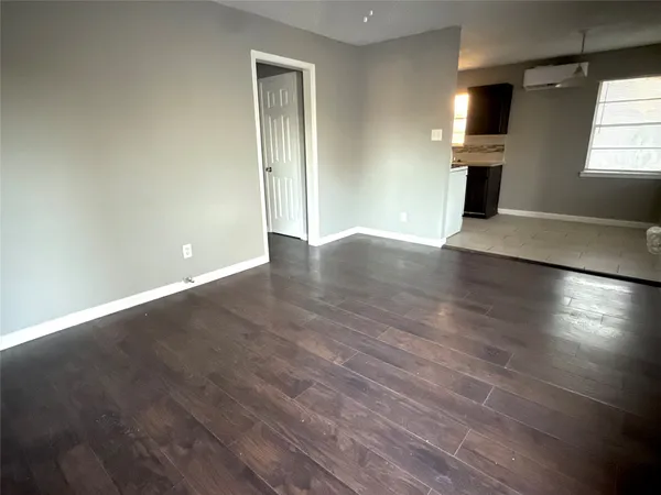an empty room with wooden floor fireplace and windows