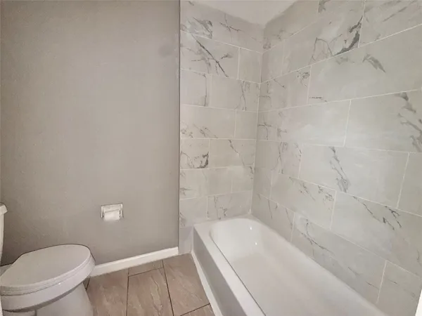 a bathroom with a granite countertop bathtub shower and toilet