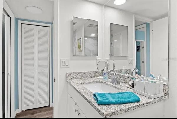 a bathroom with a granite countertop sink a mirror a bathtub and shower