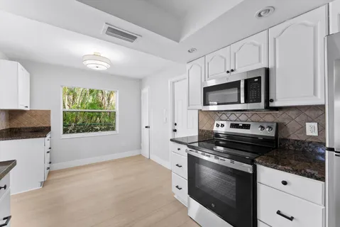 a kitchen with granite countertop a stove a sink and a microwave