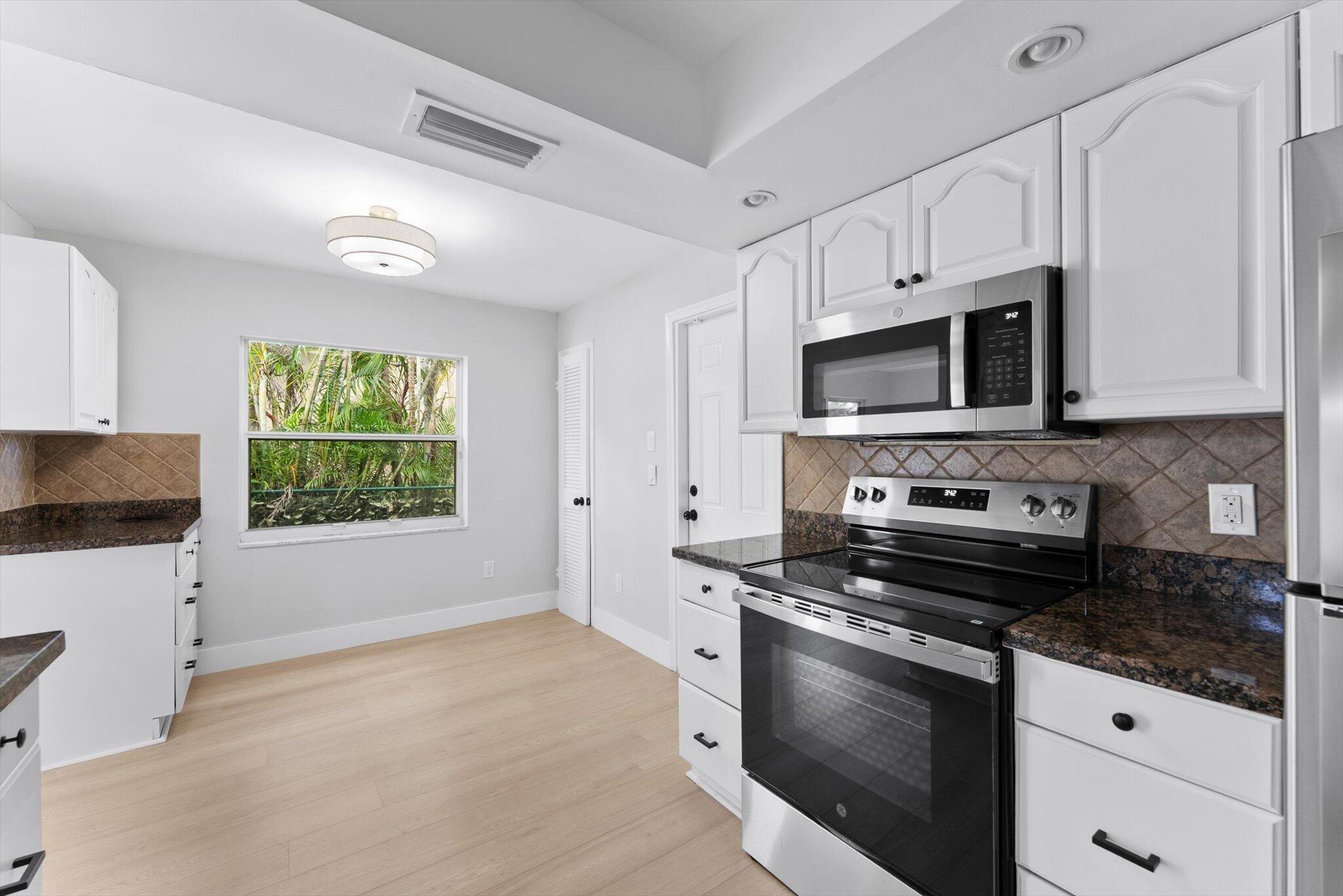 22267 Southwest 57th Avenue Boca Raton, FL 33428 - Photo 11 of 30 a kitchen with granite countertop a stove a sink and a microwave