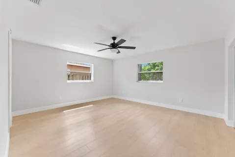 an empty room with windows and ceiling fan