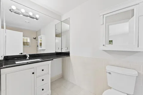 a bathroom with a granite countertop sink mirror and toilet