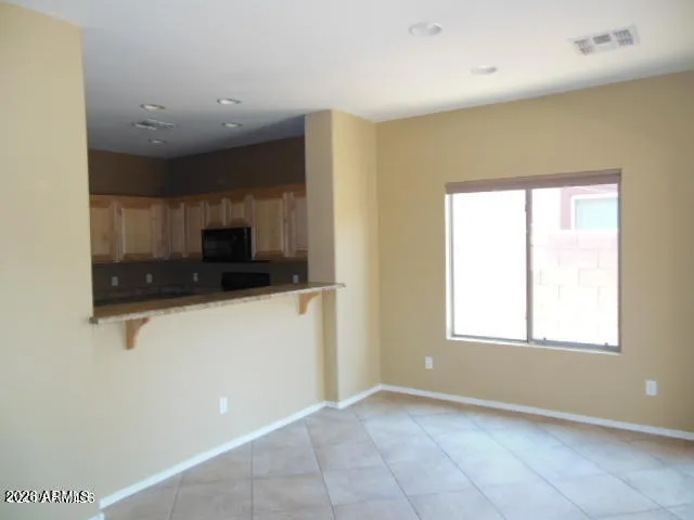 a view of an empty room with a window and a kitchen