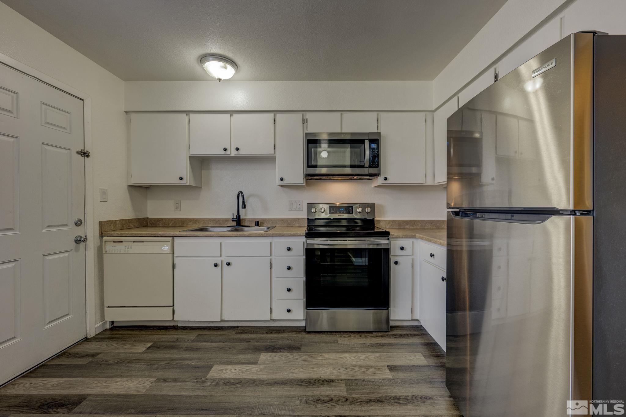 1424 East 9th Street, Unit 3 Reno, NV 89512 - Photo 7 of 26 a kitchen with stainless steel appliances granite countertop a refrigerator stove a sink and white cabinets