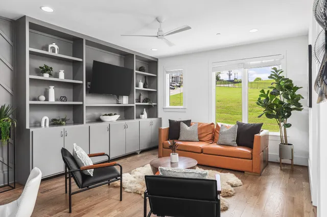 a living room with furniture a flat screen tv and a large window