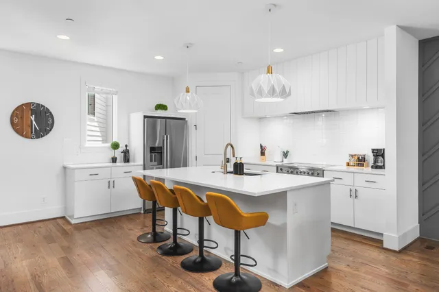 a kitchen with a sink a stove a refrigerator and island with wooden floor