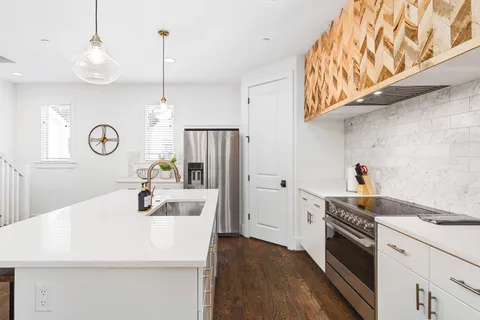 a kitchen with a sink a stove and wooden floor