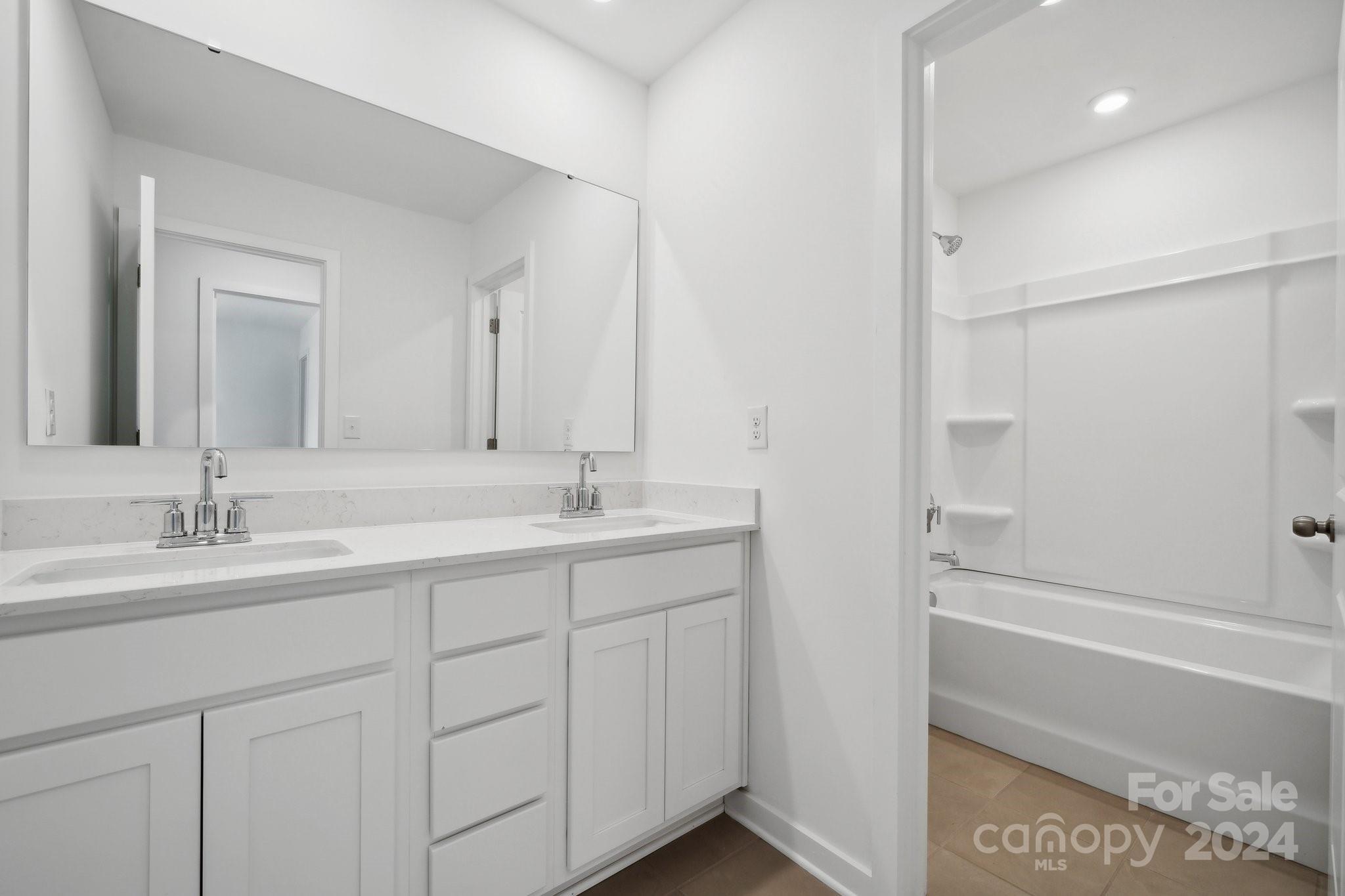 2568 Blue Sky Mdws Drive Monroe, NC 28110 - Photo 13 of 28 a bathroom with a double vanity sink a mirror and a shower