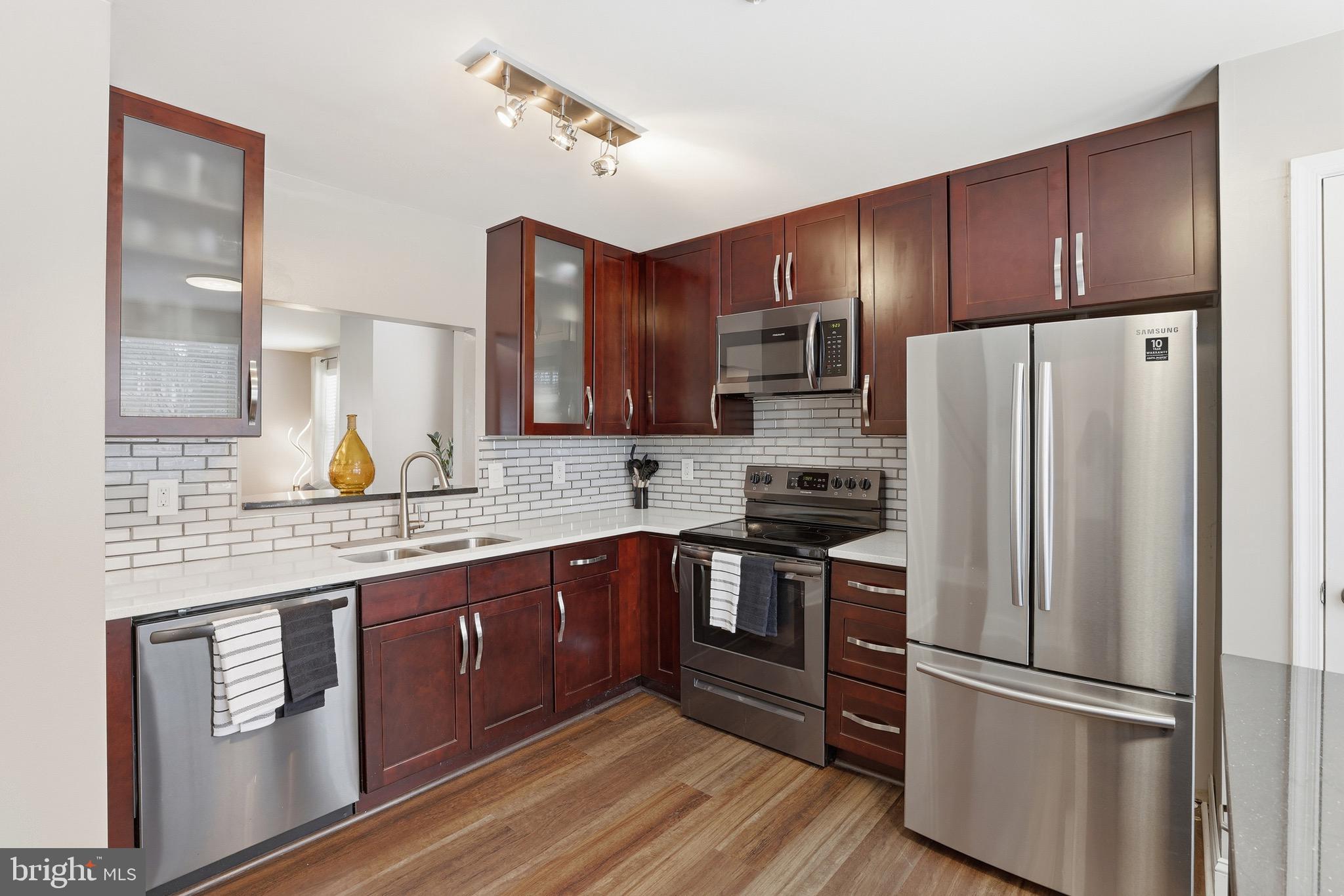10724 Kitchener Court Bowie, MD 20721 - Photo 9 of 31 a kitchen with stainless steel appliances granite countertop a refrigerator stove a sink and dishwasher with wooden floor