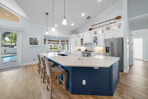 a room with stainless steel appliances kitchen island granite countertop a table chairs and a refrigerator