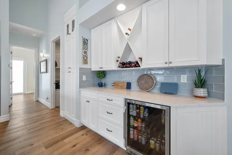 a kitchen with stainless steel appliances granite countertop a refrigerator a stove and white cabinets with wooden floor