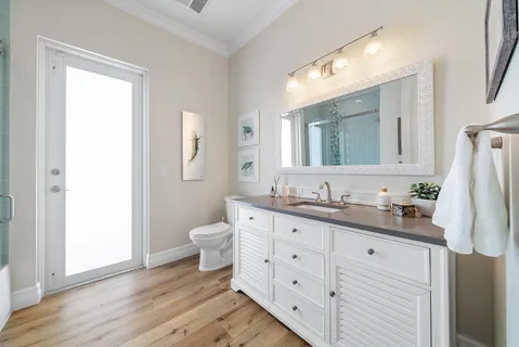 a spacious bathroom with a double vanity sink a mirror and a toilet