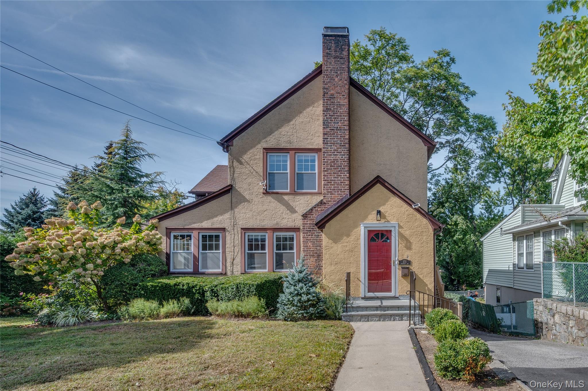 English style home featuring stucco siding, a chimney, and a front lawn