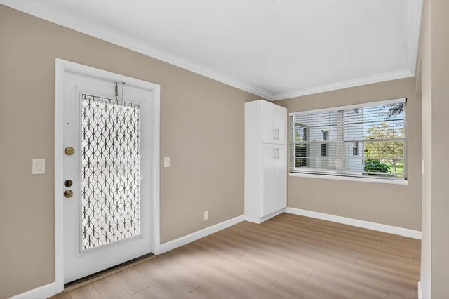 a view of an empty room with wooden floor and a window