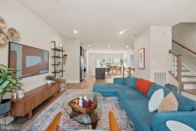 a living room with furniture kitchen view and a large window